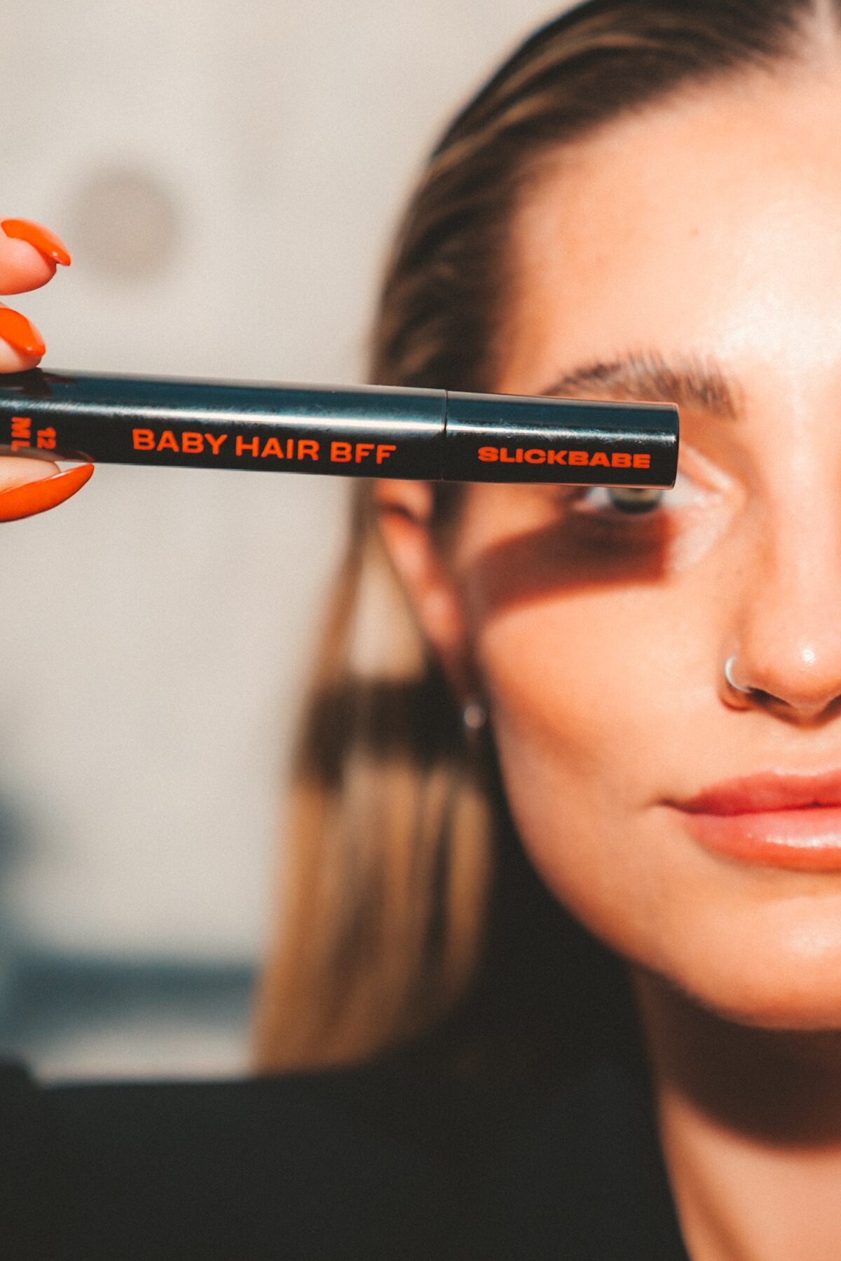 Close-up of SLICKBABE Baby Hair BFF precision wand held across face — flagship product editorial