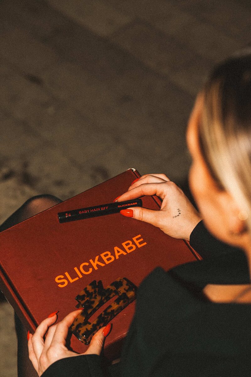 Holding SLICKBABE box with Baby Hair BFF wand and tortoiseshell clips — product unboxing detail